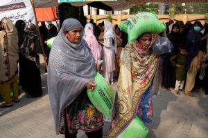 Gratë largohen me thesin e tyre falas me miell gruri në një pikë shpërndarjeje në Lahore, Pakistan. Foto: AP