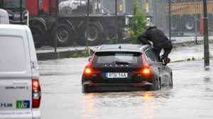 Një burrë del nga dritarja e veturës që po lëvizte në një rrugë të vërshuar në Arlöv, të Suedisë, më 7 gusht 2023. Foto: AFP