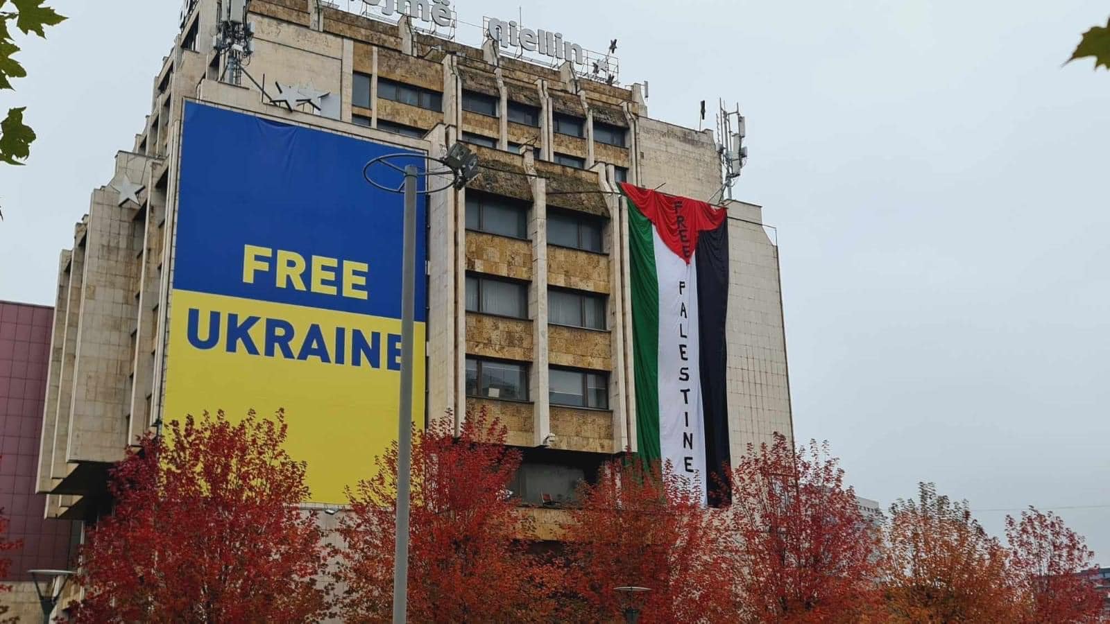 Fotografia është realizuar nga Enes Bërveniku më datë 11 nëntor të vitit 2023, ku shihet flamuri i Palestinës me mbishkrimin “Liri për Palestinën” po ashtu edhe flamuri i Ukrainës me mbi shkrimin “Liri për Ukrainën” mbi Hotel Grand në Sheshin “Zahir Pajaziti”