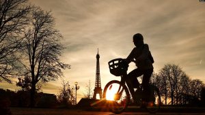 Një grua me biçikletë kalon, teksa në prapavijë shihet Kulla Eiffel. 22 nëntor 2023.