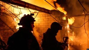 Zjarrfikësit duke shuar një zjarr pas bombardimeve ruse në Herson.