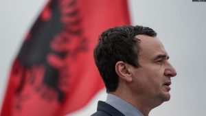 Kryeministri i Kosovës, Albin Kurti, ndërsa në sfond shihet flamuri shqiptar.