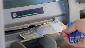 Një person duke tërhequr dinarë nga një bankomat në Mitrovicë të Veriut.