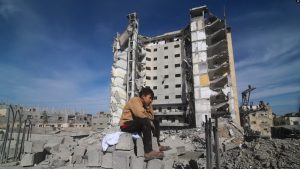Një djalosh palestinez ulet në gërmadhat e një ndërtese të rrënuar nga lufta në Rripin e Gazës, 9 mars 2024.