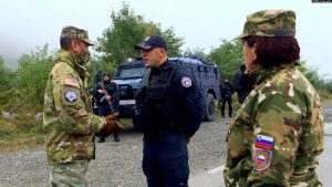 Një ushtare sllovene duke shikuar teksa një ushtar amerikan bisedon me një pjesëtarë të Policisë së Kosovës në Jarinjë.