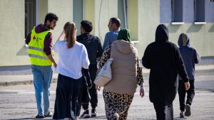 Një vullnetar i Kryqit të Kuq së bashku me një grup azilkërkuesish në një qendër për migrim në Gjermani. Shtator 2023.