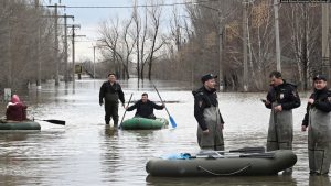 Zyrtarët policorë e vëzhgojnë një zonë të Orskut në Rusi, teksa njerëzit përdorin barka prej gome, si pasojë e vërshimeve nga shkrirja e borës.