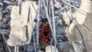 Një vajzë duke shpëtuar sende nga rrënojat e një ndërtese të shembur në Gazë, më 24 prill 2024.