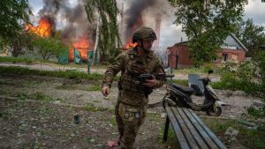Një ushtar kalon pranë një shtëpie të kapluar nga zjarri si pasojë e sulmeve ruse në Vavçansk, Ukrainë, 11 maj 2024.